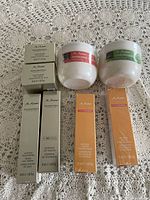 Photo of 8 M. Asam skincare items including boxes and jars on a lace cloth.