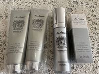 Four M. Asam Vinolift products on lace tablecloth: two neck and decollete cream tubes, remodeling serum bottle, boxed eye serum