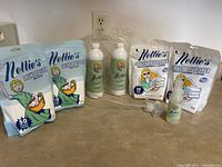 Full lot of Nellie's laundry products on a countertop including 2 bags of Laundry Soda, 2 bags of Oxygen Brightener, 2 spray bottles with sprayers and 1 small bottle of wrinkle spray.