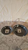 Two GreenPan non-stick frying pans (8.5" and 11.5" diameters) shown from overhead on patterned tablecloth.