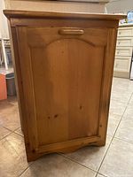 Full view of one oak receptacle showing front wood panel door with handle and decorative arch design.