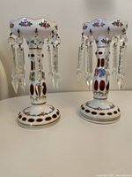 Front view of both lusters showing scalloped bowls, stems, bases and hanging crystal prisms