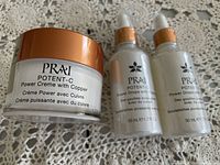 Photo of PRAI Potent-C Power Creme with Copper jar and three bottles of Power Drops with Copper, showing the brand label and product type.