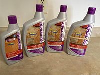 Four bottles of Rejuvenate floor restorer placed on a counter, all sealed with purple caps.