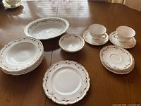 Full set of china on table showing 2 teacups with saucers, 6 bowls, 2 small bowls, 1 serving dish, and several plates including a dessert plate
