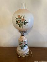 Front view of the lamp showing the floral glass globe, base, and attached power cord