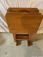 Set of four wood folding tray tables stacked together, showing rectangular tops and foldable legs.