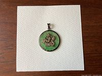 Front view of the round pendant showing the green jade center and the silver dragon design mounted on it, highlighting the detail and condition.