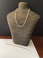 18K yellow gold tennis-style necklace displayed on a stand with matching bracelet laid in front