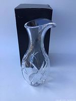 Clear etched crystal vase with flared rim and tapered body next to its original box showing wear.