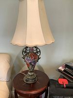 Full view of the lamp including cream silk shade and ceramic hand painted vase base on a wooden table