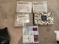 Five bedding packages laid out on carpet, four HomeSuite Collection sets and one Tranquil Nights set, one HomeSuite package opened.