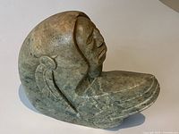 Side view of Steve Hawk soapstone sculpture showing carved face and wing detail