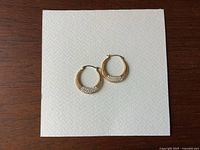 Front view of the pair of vintage 10K yellow gold hoop earrings with imitation diamonds visible on the front lower portion.