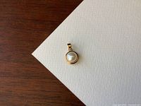 Top-down view of the pendant showing the round cultured pearl center set in the gold bezel.