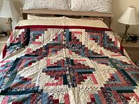 Full view of the quilt spread across a queen size bed, showing the overall color scheme and patchwork design with prominent red border.