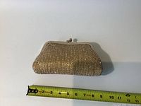 Clutch purse laid flat beside measuring tape showing approximately 8 inches width.
