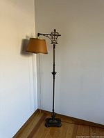 Full view of the antique brass floor lamp standing against a white wall on wooden floor.