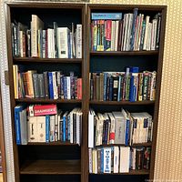 Front view of two dark wood bookshelves filled with a variety of books mainly on computing, programming, engineering, and reference topics.