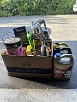 Box of assorted car maintenance materials including motor oil, primer paint, antifreeze, and various automotive fluids