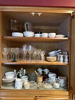 Full view of kitchen cabinet shelves with vintage glasses and ceramics arranged.