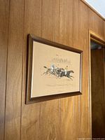 Image of framed 'La Course' art print on wood paneled wall, showing overall view of the artwork and frame.