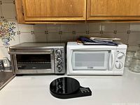 Photo showing Oster toaster oven and white Commercial Chef microwave on the kitchen counter, along with a black digital kitchen scale in front.