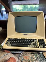 Front angle view showing the cream-colored case and integrated keyboard of the Televideo Model 910 terminal with powered on screen.