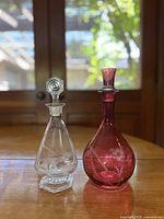Pair of glass decanters on wooden surface with natural light, showing shape and color differences.