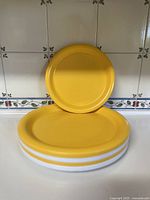 Five stacked vintage Ingrid Chicago plates in yellow and white.