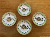 Top view of four plates arranged on wooden surface showing central tiger and crane motif and border pattern