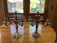 Pair of silver candelabras displayed on wooden table in front of glass doors