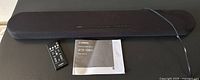 Photo shows Yamaha ATS-1080 sound bar, remote control, and user manual on a flat surface.