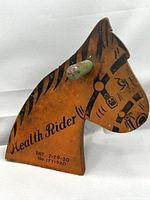 Side profile view of the wooden horse head showing painted details and green dowel handle.