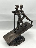 Front angled view of bronze sculpture showing two kids on scooter, front wheel visible and base shape.