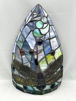 Close-up of front of faux stained glass sconce shade featuring multicolored dragonfly design and jewelled accents