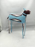 Front and side view of the handmade African beaded animal sculpture titled Blue Bokkie, showing the wire frame covered in blue, brown, and white glass beads forming a stylized antelope figure.