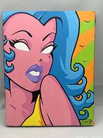 Front view of Kevin Cox 'Demon-Eyed Sweety' Pop Art painting showing vibrant pink female figure with blue hair, yellow top, and orange-green background, signed at bottom right.