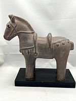 Front left profile view of terracotta horse sculpture on black wooden base against neutral background.