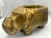 Side view of the ceramic hippopotamus bowl showing textured surface and four stout legs.