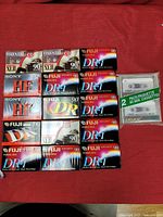 Full overview of all 17 blank audio cassette tapes laid out on red fabric, featuring Maxell, Fuji, and Sony brands
