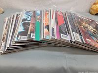 Stack of 40 comic books laid on a table, showing a variety of cover colors and styles.