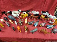 Overview of all 40 animal figures on red fabric background showing a variety of farm and zoo animals including horses, lions, and birds.