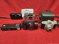 Front view of the 5 film cameras grouped together on a red background.