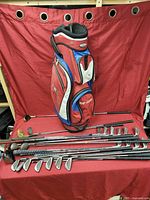 Full view of Top Flite golf bag with golf clubs displayed on a red fabric background
