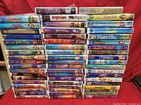 Full lot of Disney and related kids VHS tapes showing spines with titles and colorful cases stacked in rows