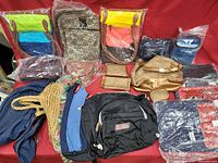All purses, backpacks, and bags arranged on a red cloth background showing variety, styles and materials.
