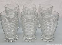 Set of six clear glass Anchor Hocking Manhattan tumblers with ribbed horizontal lines and bubble-patterned bases.