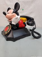 Left side angle of vintage Disney Mickey Mouse desk phone showing Mickey figure and handset.