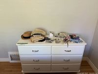 Front view of white 6-drawer IKEA Tyssedal dresser with personal items on top.
